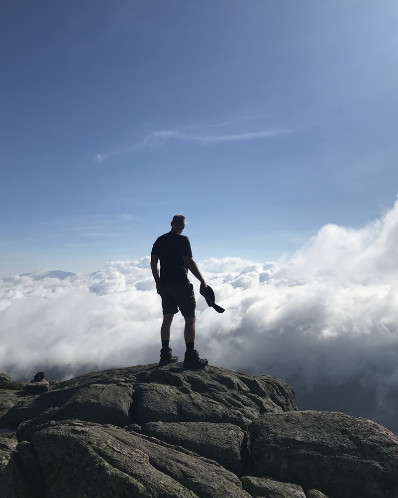 Jeffrey C. Hood standing on a rocky summit above a sea of clouds